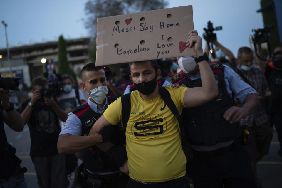 Police remove a Barcelona soccer fan from the Camp Nou stadium during a protest against the club's president Josep Maria Bartomeu, in Barcelona, Spain, Wednesday, Aug. 26, 2020. Lionel Messi has told Barcelona he wants to leave the club after nearly two decades with the Spanish giant. (AP Photo/Felipe Dana)