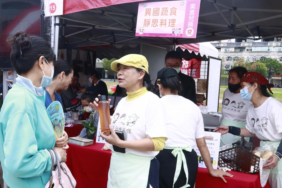 異國蔬食靜思料理攤位上，志工嚴玉女忙著跟民眾介紹推廣蔬食料理。