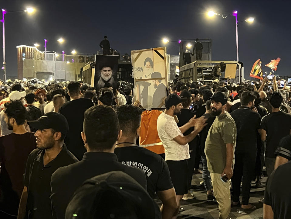 Protesters gather in Baghdad's Tahrir Square, carrying Iraqi flags and images of influential Iraqi Shiite cleric and political leader Muqtada al-Sadr, Saturday, July 22, 2023, following reports of the burning of a Quran carried out by a ultranationalist group in front of the Iraqi Embassy in Copenhagen. Protesters attempted to cross the Jumhuriya bridge leading to the Green Zone, where the Danish embassy is, but were pushed back by security forces. (AP Photo/Ali Jabar)