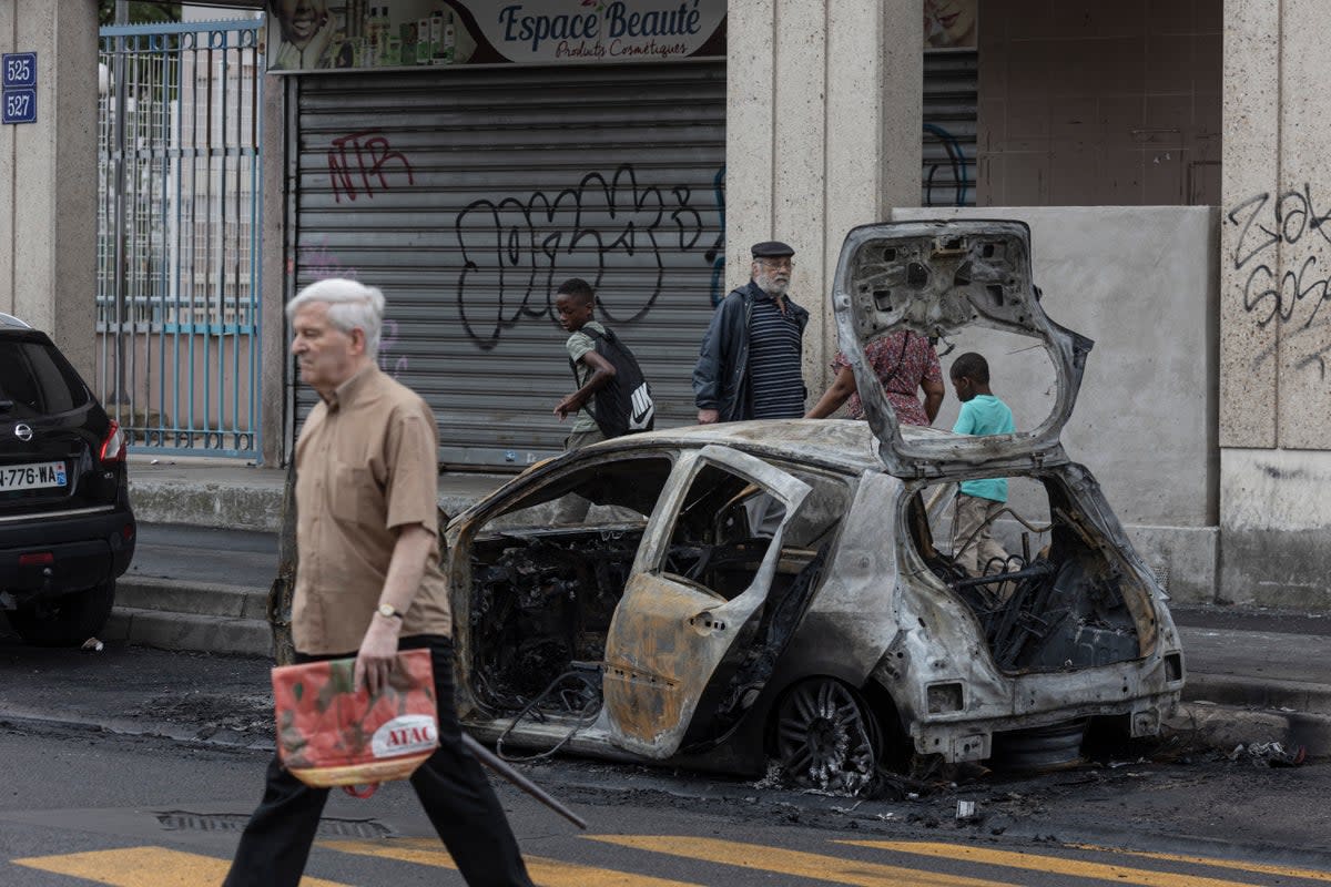 The scorched remains of a car remain by the side of a major roadway follwing rioting (Getty Images)
