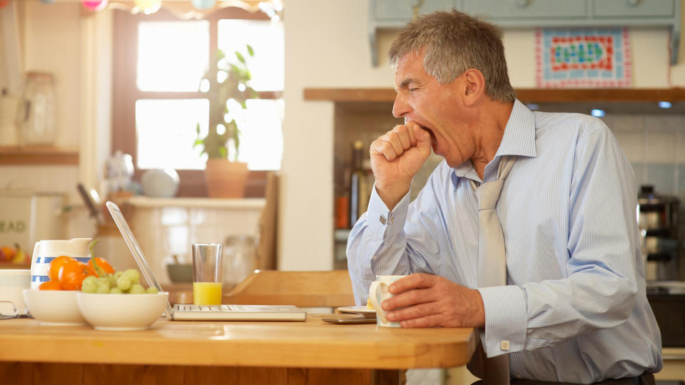 man yawning at his kitchen table