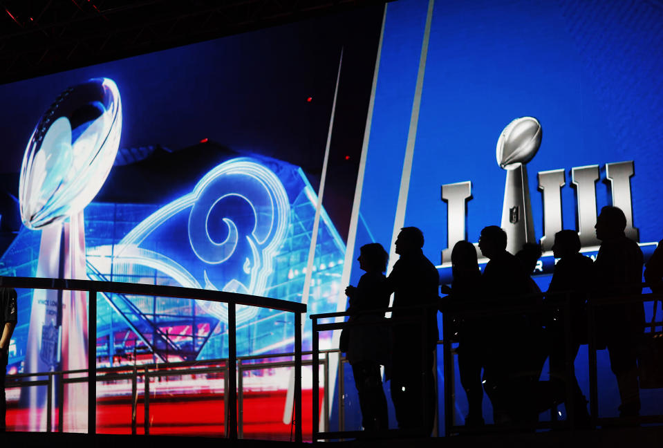 Fans line up in front of a big screen to have their photo taken with the Vince Lombardi Trophy on display at the NFL Experience ahead of Sunday's Super Bowl 53 football game between the Los Angeles Rams and New England Patriots in Atlanta, Wednesday, Jan. 30, 2019. (AP Photo/David Goldman)