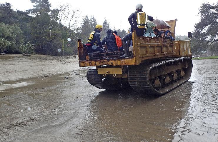 Santa Barbara County Firefighters help rescue victims by transporting them in a tractor on Friday, Jan. 20, 2017 at the El Capitan Canyon campground following flooding due to heavy rains in Gaviota, Calif. Dozens of campers were rescued and evacuated following the morning flood that swept large wooden cabins and vehicles away. (Mike Eliason/Santa Barbara County Fire Department via AP)