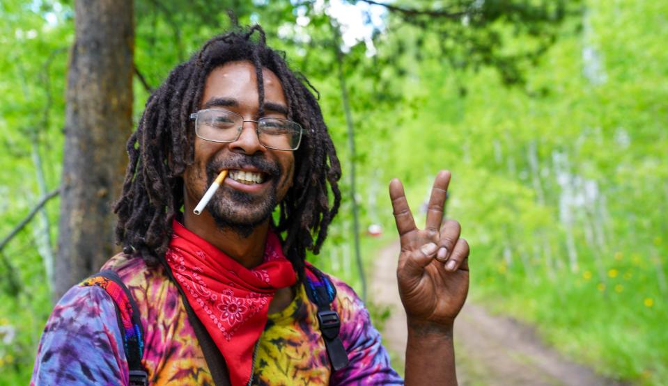 Erik Childress, 30, of Oregon flashes a peace sign while taking a break from hiking to the Rainbow Family gathering on June 26.