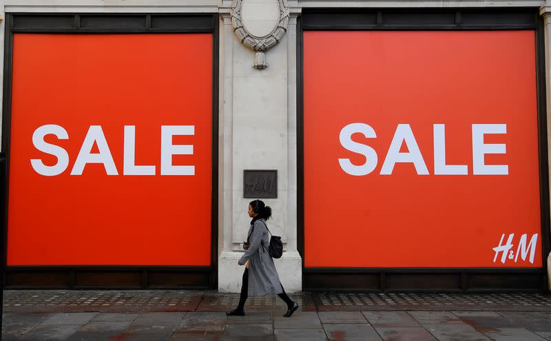 A woman walks past a sale sign on a branch of H&M on Oxford Street in London