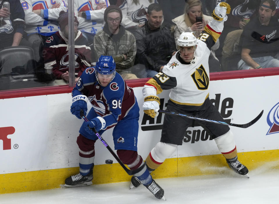 Colorado Avalanche right wing Mikko Rantanen, left, swings at the puck next to Vegas Golden Knights defenseman Alec Martinez during the first period of an NHL hockey game Wednesday, Jan. 10, 2024, in Denver. (AP Photo/David Zalubowski)