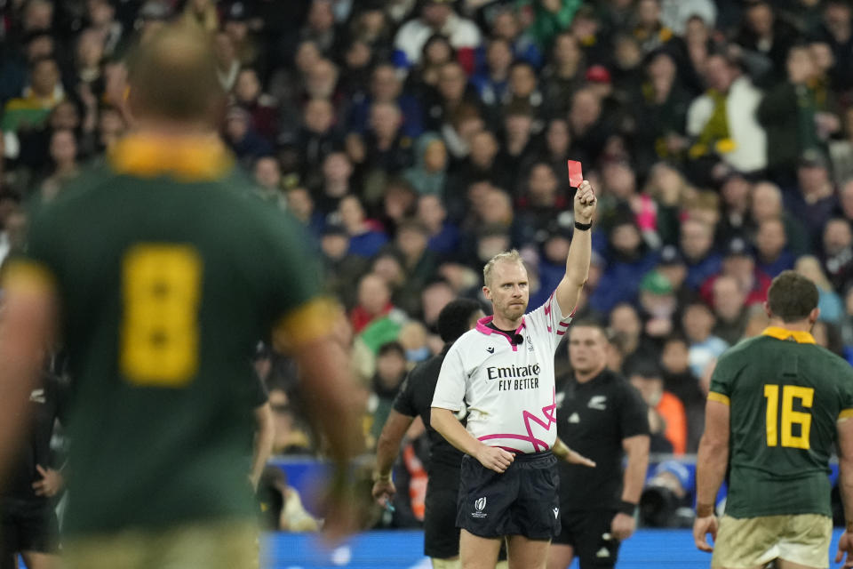 FILE - Referee Wayne Barnes holds up a red card to show that the video judge has upgraded a yellow to red for New Zealand's Sam Cane during the Rugby World Cup final match between New Zealand and South Africa at the Stade de France in Saint-Denis, near Paris Saturday, Oct. 28, 2023. English referee Barnes announced his expected retirement while expressing concerns about abuse he and his family received on social media for years. (AP Photo/Christophe Ena, File)