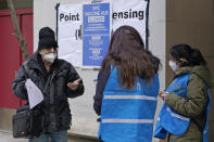 A man who came to get a COVID-19 vaccine holds his paperwork as he talks to a New York City health department worker outside a closed vaccine hub, Thursday, Jan. 21, 2021, in the Brooklyn borough of New York. Public health experts are blaming COVID-19 vaccine shortages around the U.S. in part on the Trump administration's push to get states to vastly expand their vaccination drives to reach the nation's estimated 54 million people age 65 and over. The push that began over a week ago has not been accompanied by enough doses to meet demand, leading to frustration and confusion. (AP Photo/Kathy Willens)