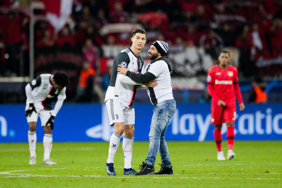 11 December 2019, North Rhine-Westphalia, Leverkusen: Soccer: Champions League, Bayer Leverkusen - Juventus Turin, Group stage, Group D, 6th matchday. Turins Cristiano Ronaldo (l) is embraced by a fan who has stormed the square. Photo: Rolf Vennenbernd/dpa (Photo by Rolf Vennenbernd/picture alliance via Getty Images)
