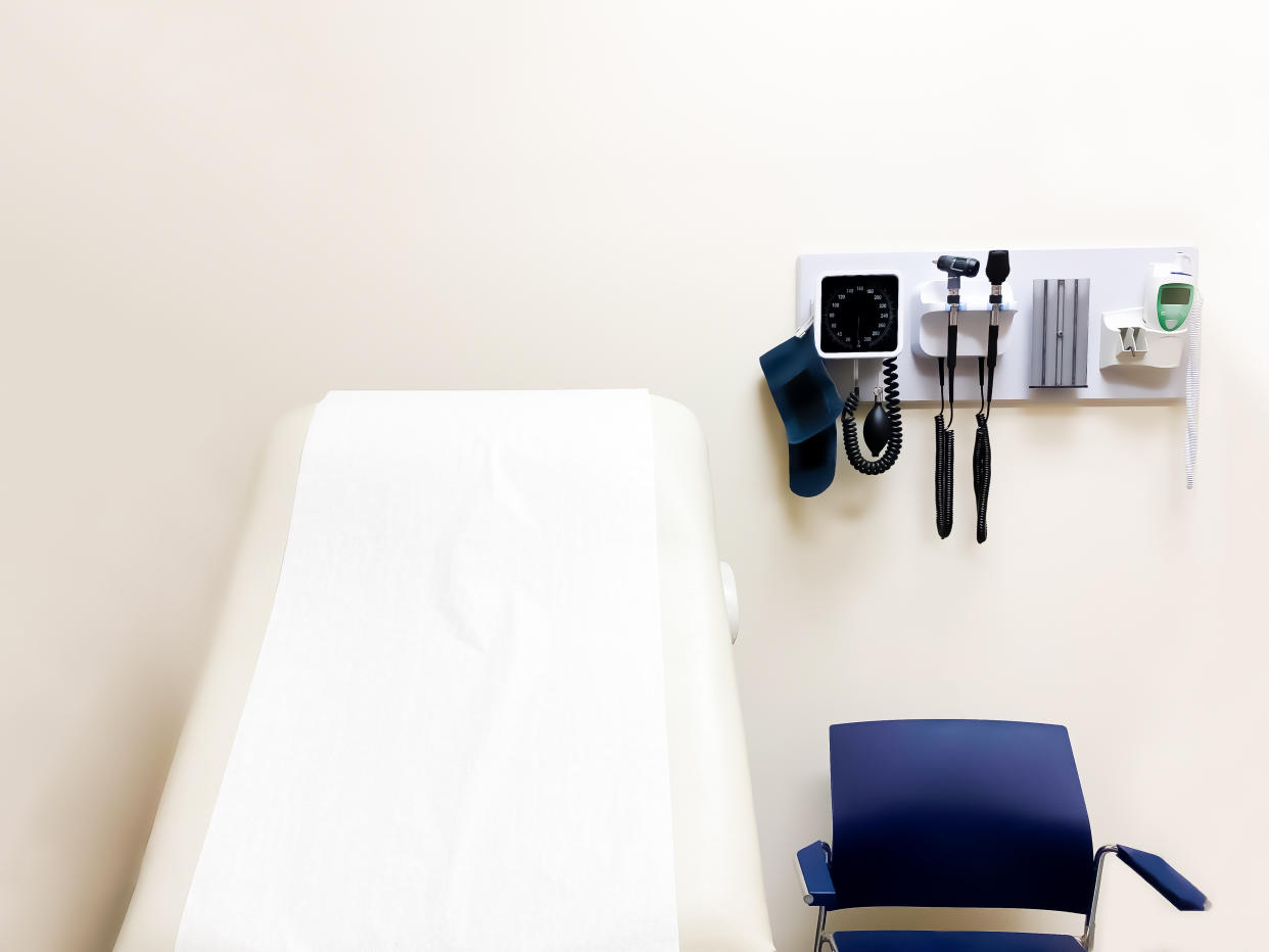 Doctor's examination room with wall-mounted medical diagnostic equipment beside standard patient examination chair