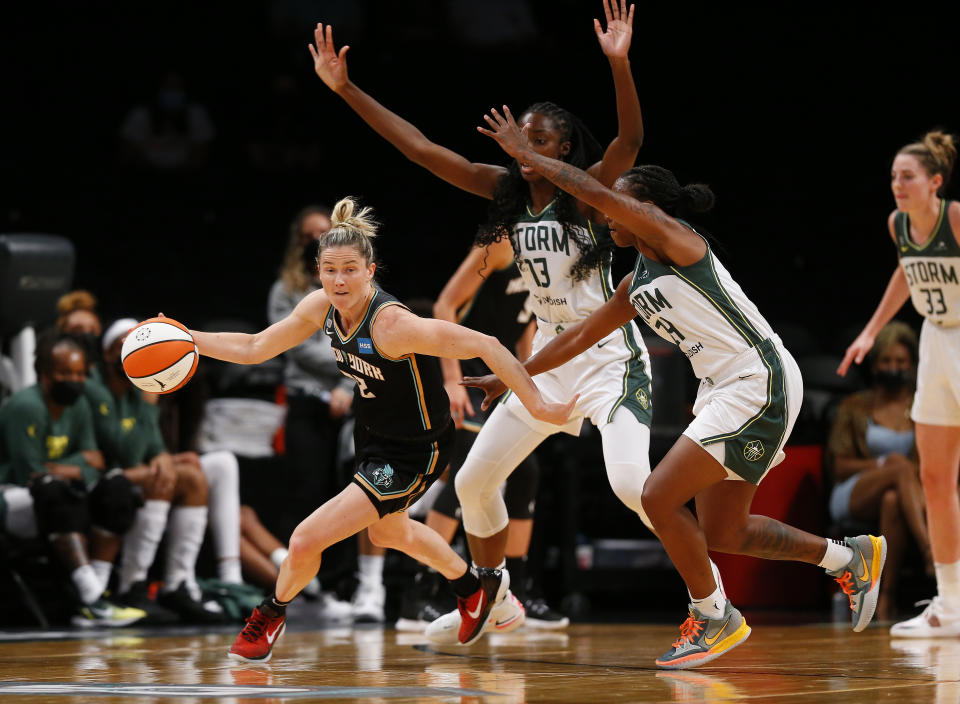 New York Liberty guard Sami Whitcomb (32) dribbles the ball against Seattle Storm defenders Ezi Magbegor (13) and Jewell Loyd (24) during the first half of a WNBA basketball game Friday, Aug. 20, 2021, in New York. (AP Photo/Noah K. Murray)