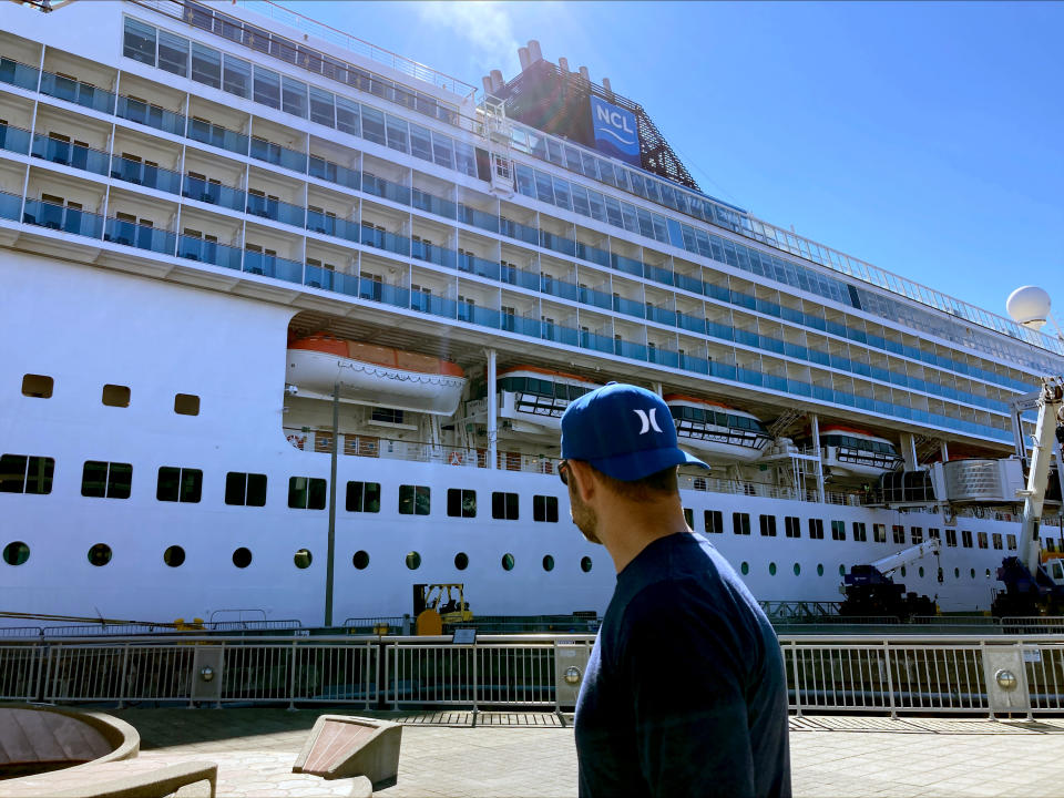 A man walks by the Norwegian Sun docked in Seattle on Tuesday June 30, 2022. The ship is in Seattle for repairs after hitting an iceberg June 25 off Alaska. (AP Photo/Manuel Valdes)