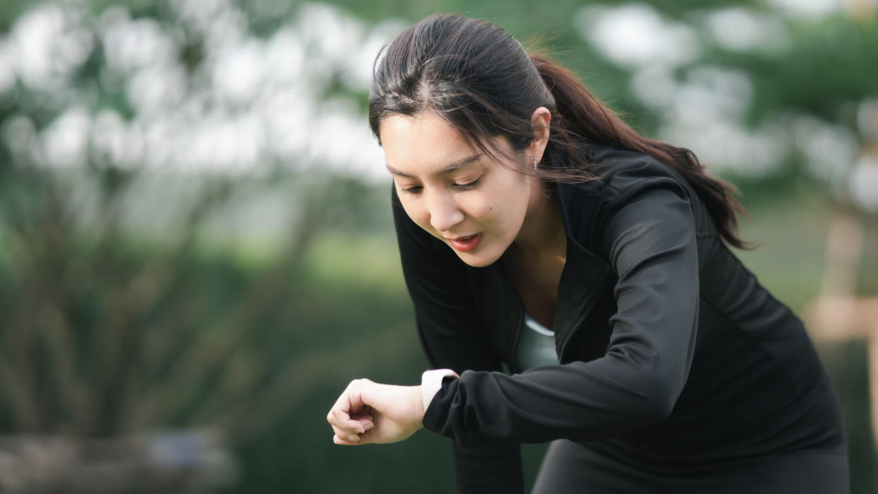 Young woman checking sports watch after a run. 