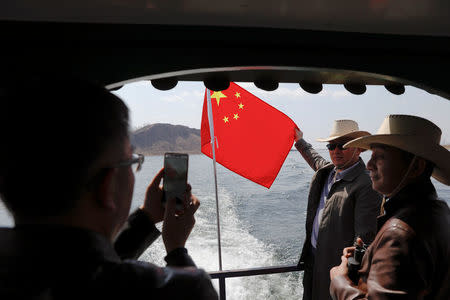 Tourists pose with Chinese flag on a boat taking them from the Chinese side of the Yalu River for sightseeing close to the the shores of North Korea, near Dandong, China's Liaoning province, April 1, 2017. REUTERS/Damir Sagolj
