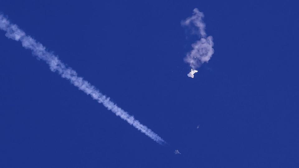 In this photo provided by Chad Fish, the remnants of a large balloon drift above the Atlantic Ocean, just off the coast of South Carolina, with a fighter jet and its contrail seen below it, Feb. 4, 2023. (Chad Fish via AP, File)