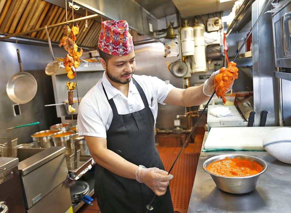 Sous chef Akash Gotame skewers curry seasoned chicken at Turmeric House in Weymouth on Tuesday, June 27, 2023.