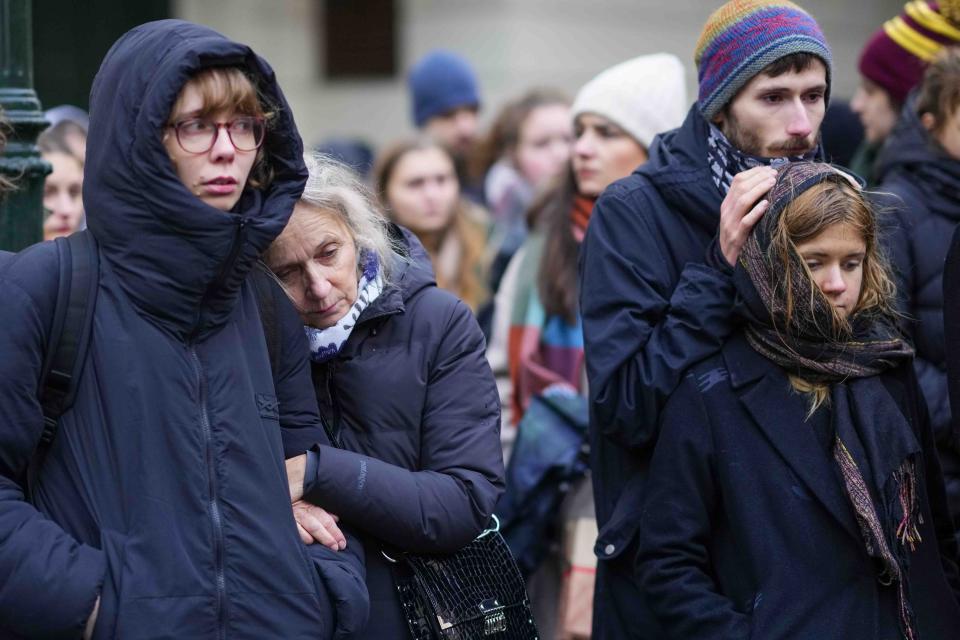 Mourners stand outside the headquarters of Charles University after mass shooting in Prague, Czech Republic, Friday, Dec. 22, 2023. A lone gunman opened fire at a university on Thursday, killing more than a dozen people and injuring scores of people. (AP Photo/Petr David Josek)