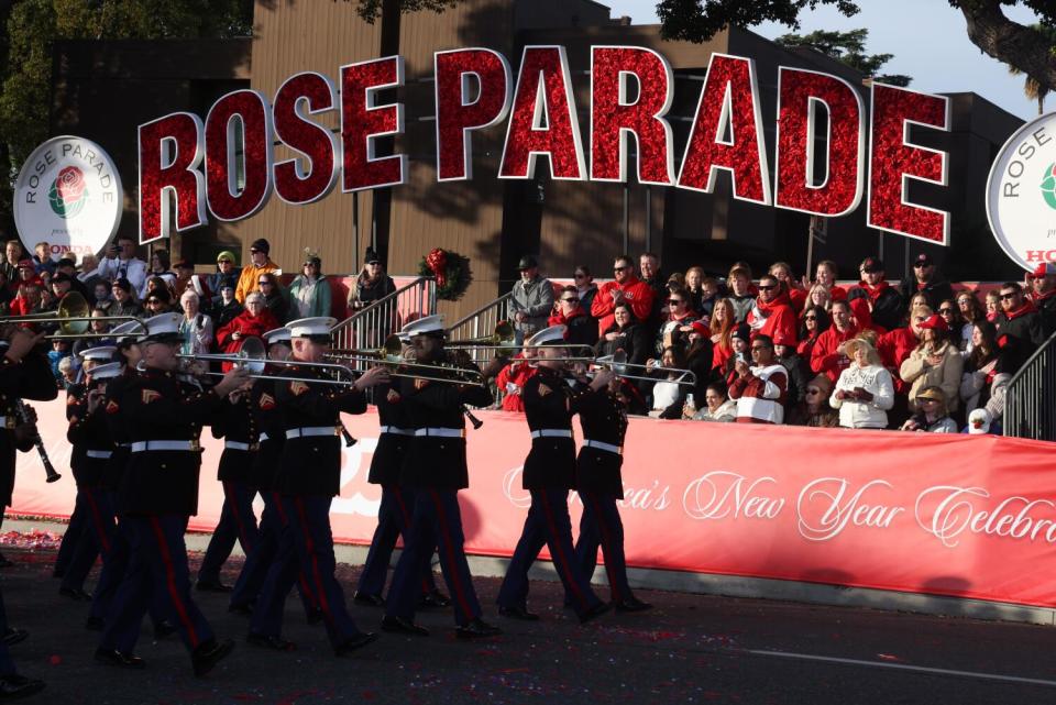 A Marine Corps marching band passes under a Rose Parade banner