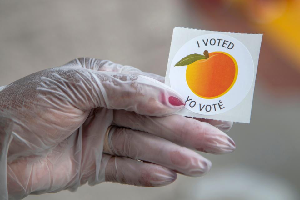 An early voter, who wore gloves to cast their ballot, shows off their sticker during Georgia's primary election at the Gwinnett County Voter Registration and Elections Office in Lawrenceville, Georgia, May 18, 2020.