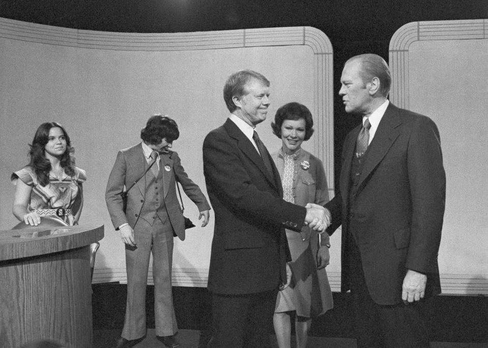 FILE - In this Oct. 6, 1976 file photo with his wife Rosalynn Carter looking on at center, Democratic presidential candidate Jimmy Carter, center left, shakes hands with President Gerald Ford at the conclusion of their debate at the Palace of Fine Arts Theater in San Francisco, Calif. (AP Photo, File)