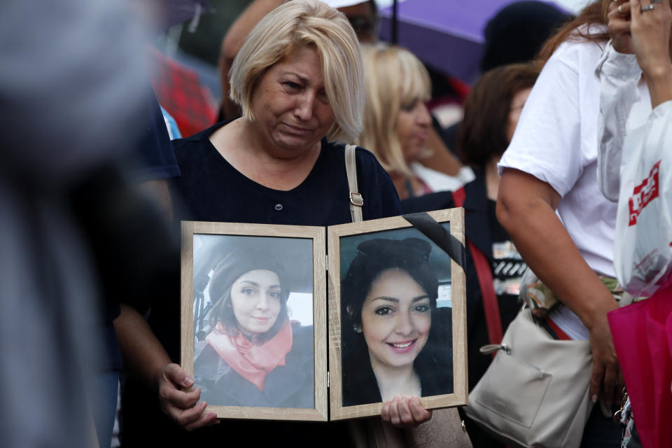 A woman carrying pictures of her late relative, protests in front of the Government building in Skopje, North Macedonia, on Monday, Sept. 4. 2023. Thousands have gathered late on Monday in front of the government in North Macedonia's capital Skopje to protest on scandal that broke after media reported that employees in the state running Clinic of Oncology allegedly were selling on a black market a million of dollars' worth clinic supply of drugs needed for cancer treatment. (AP Photo/Boris Grdanoski)