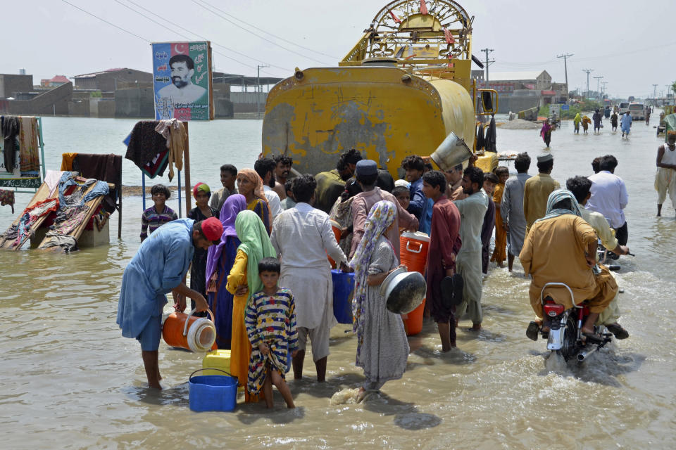 People jostle to get drinking water from a municipality water truck on a flooded road, in Sohbatpur, a district of Pakistan's southwestern Baluchistan province, Monday, Aug. 29, 2022. International aid was reaching Pakistan on Monday, as the military and volunteers desperately tried to evacuate many thousands stranded by widespread flooding driven by "monster monsoons" that have claimed more than 1,000 lives this summer. (AP Photo/Zahid Hussain)