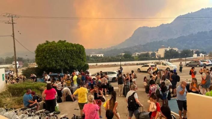 Humo en Rodas mientras la gente espera afuera de un hotel