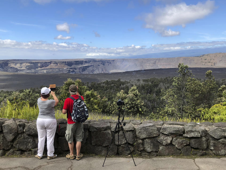 This Saturday, Sept. 22, 2018 photo released by the National Park Service shows tourists on the first day the park was reopened after volcanic activity forced Hawaii Volcanoes National Park to close for more than four months in Hawaii. The eruption destroyed hundreds of homes outside the park while changing the popular summit crater inside the park. (Janice Wei/National Park Service via AP)