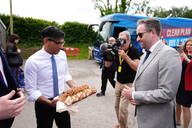 Rishi Sunak handing out Bara Brith cake to the media during a visit to a farm shop in Mold