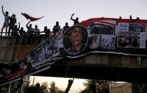 Protesters tear down a banner with a picture of Sudan's head of transitional council, Lieutenant General Abdel Fattah Al-Burhan Abdelrahman and pictures of Sudanese soldiers and protesters together, minutes after it was hanged to a railroad bridge near the Defence Ministry in Khartoum, Sudan, April 20, 2019. REUTERS/Umit Bektas