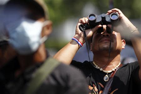 Anti-government protesters scan the area as they gather on the main road outside the headquarters of the Royal Thai Police in central Bangkok March 4, 2014. REUTERS/Damir Sagolj