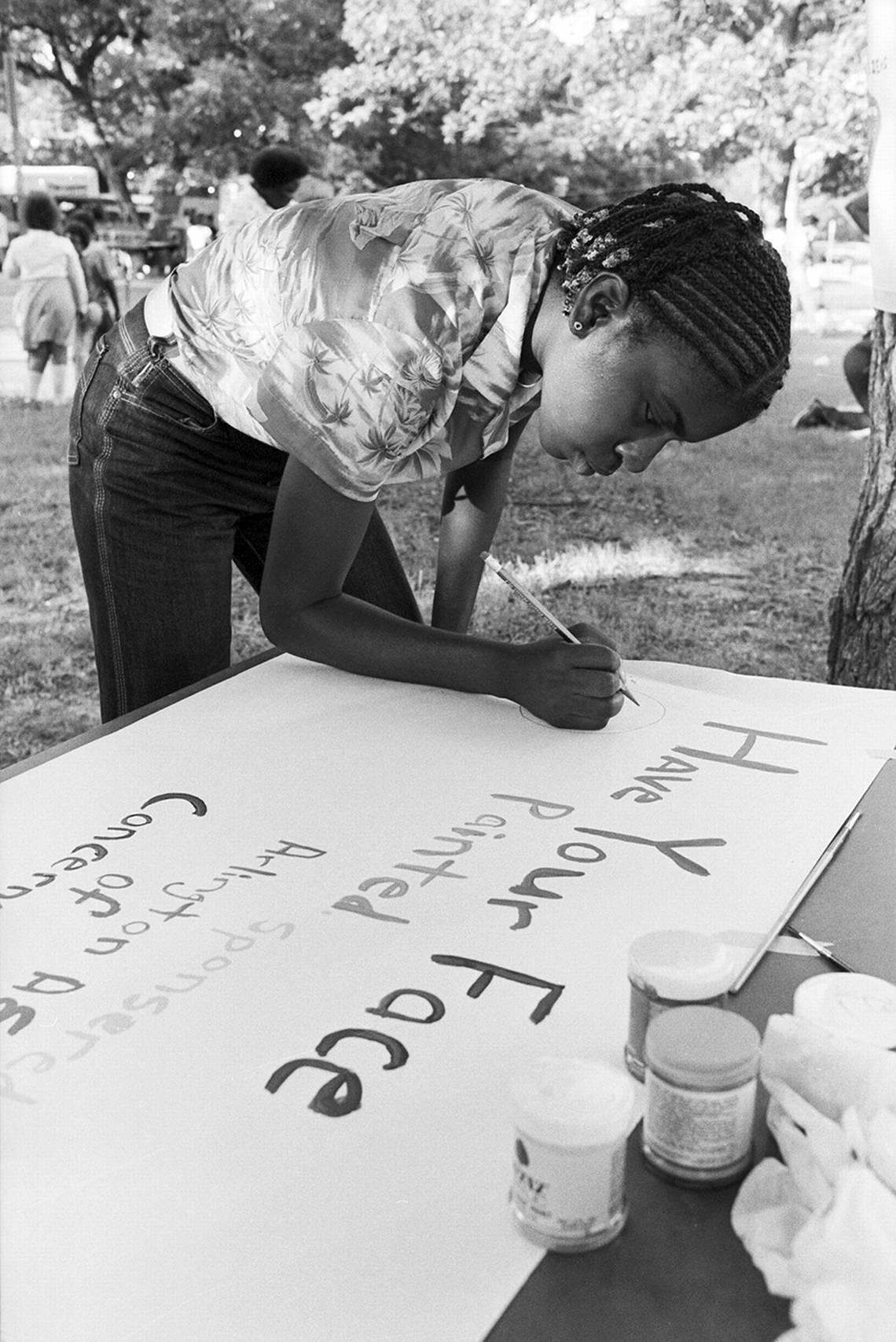 A young girl prepares a sign for a face painting station for the Juneteenth festivities in Sycamore Park in Fort Worth in 1981.