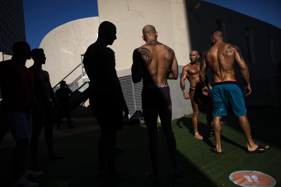 Contestants exercise backstage during the National Amateur Body Builders Association competition in Tel Aviv, Israel, Wednesday, Aug. 19, 2020. Because of the coronavirus pandemic, this year's competition was staged outdoors in Tel Aviv. The 85 participants were required to don protective masks in line with health codes. (AP Photo/Oded Balilty)