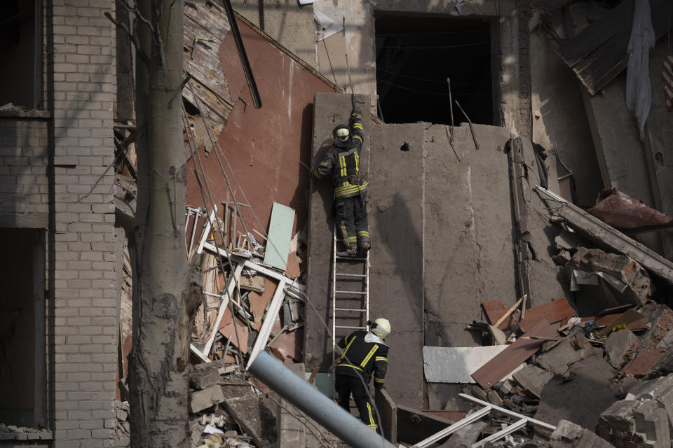 Rescue workers clear the debris at the scene where a woman was found dead after a Russian attack that heavily damaged a school in Mykolaivka, Ukraine, Wednesday, Sept. 28, 2022. (AP Photo/Leo Correa)