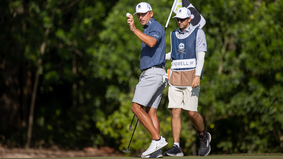 Charles Howell III lifts his ball to the crowd as his caddy replaced the pin behind him.