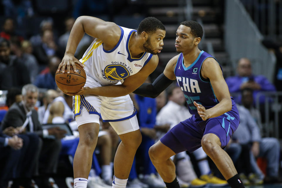 Golden State Warriors forward Omari Spellman, left, looks to pass the ball as Charlotte Hornets forward P.J. Washington defends during the first half of an NBA basketball game in Charlotte, N.C., Wednesday, Dec. 4, 2019. (AP Photo/Nell Redmond)