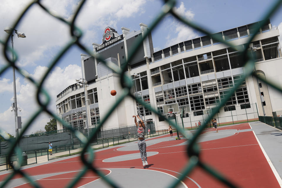 FILE - In this May 18, 2019 file photo The Ohio State University's football stadium looms above neighboring basketball courts in Columbus, Ohio. Mike Drake, the president of The Ohio State University says he'll retire from that role next year. Drake's five-year tenure at one of the nation's largest universities has included strategic successes, such as record numbers for the school in applications, graduates, research expenditures and donor support. But it also has been marred by scandals involving the university's marching band, a prominent football coach and a former team doctor accused of widespread sexual abuse. (AP Photo/John Minchillo, File)