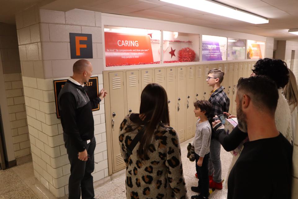 North Canton Middle School Principal David Eby, left, shows the family of 1960 Hoover High grad Patty Rumfola her old locker. Rumfola's lost purse was found in 2019 between the wall and locker.