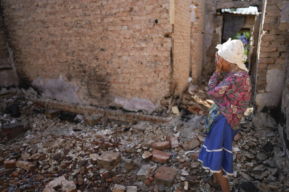 Hanna Sylivon, de 76 años, se cubre el rostro al ver su casa destruida por ataques rusos, el domingo 19 de junio de 2022, en Cherníhiv, Ucrania. (AP Foto/Natacha Pisarenko)