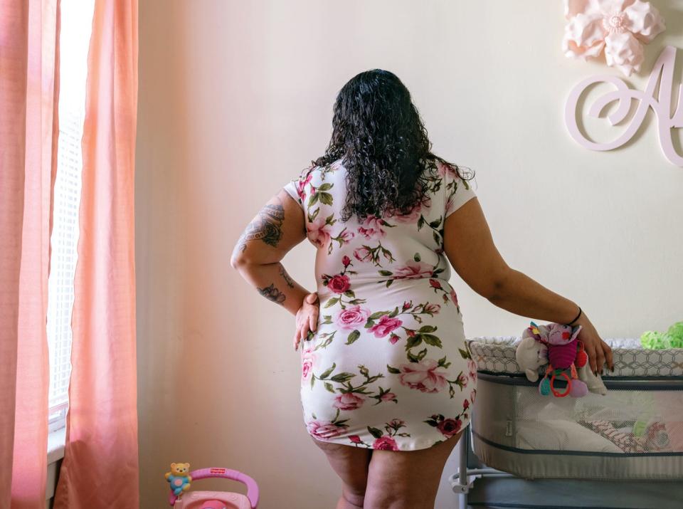 M. stands next to the crib in the room she created for her daughter, who is in foster care.