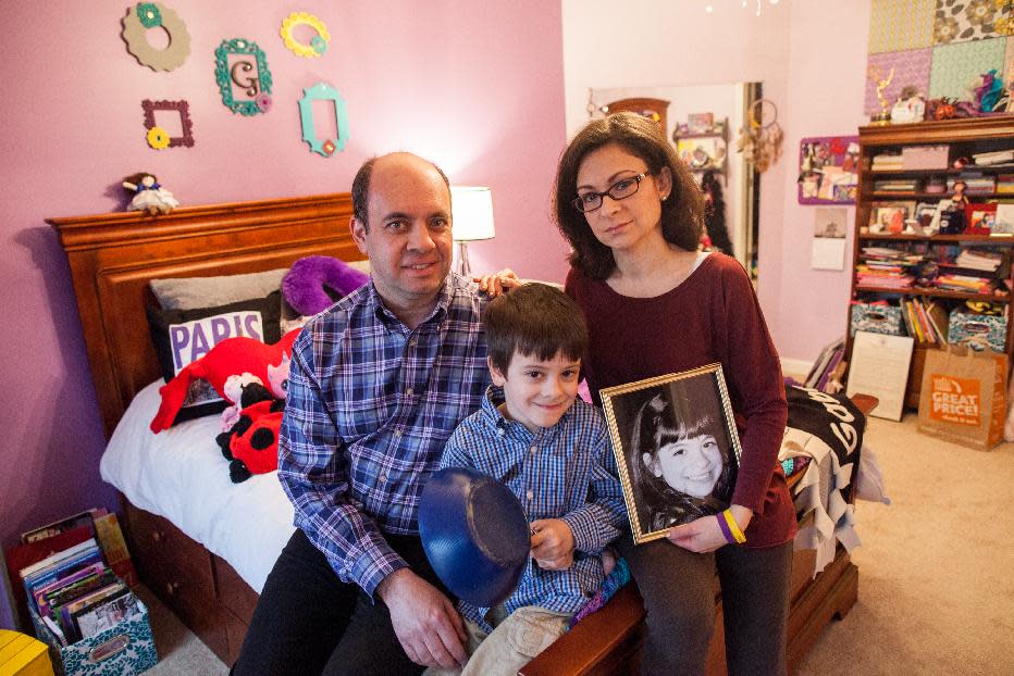 Mark Miller, left, Ellyn Miller, right, and their son Jake, center, pose for a portrait in their daughter, Gabriella's bedroom at their home in Leesburg, Va., on Wednesday, March 12, 2014. The Senate passed a bill, named for Gabriella, Tuesday that directs $126 million over the coming decade for childhood cancer research. (AP Photo/Zach Gibson)