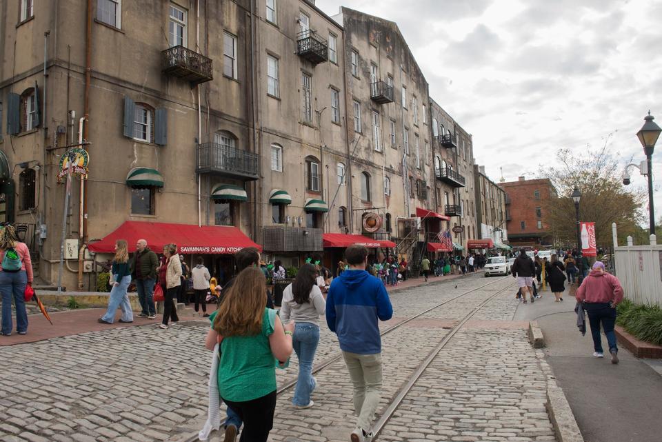 Visitors and locals walk down River Street the day after St. Patrick's Day. 