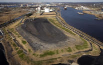 FILE - This Friday, Feb. 29, 2008, photo shows an aerial view of the fly ash landfill at Dominion's Chesapeake Energy Center in Chesapeake, Va. Millions of tons of ash stored at the former coal-fired power plant in the city will become increasingly vulnerable to flooding and other coastal risks. Virginia and its public utilities struggle to cope with the coal ash buried in pits and ponds across the state, tons more of the industrial byproduct is being imported each year. (Bill Tiernan/The Virginian-Pilot via AP)