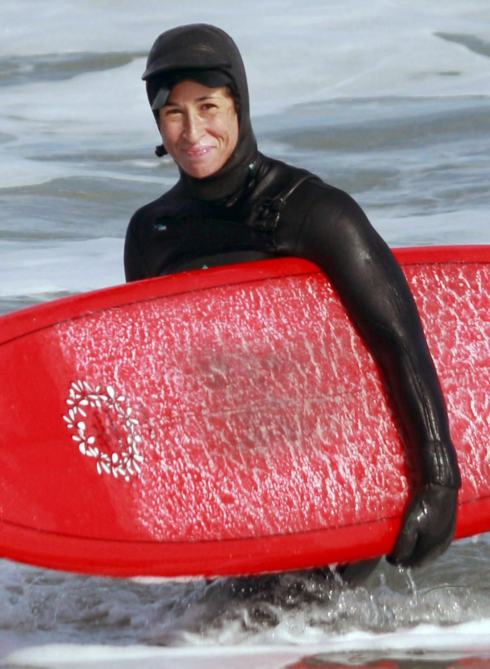 In this March 2, 2013 photo, Suzanne Turell, of York, Maine, carries a surfboard at Hampton Beach, N.H. Turell and Connie Yang made it safely down Longs Peak in Colorado Friday, Sept. 13, 2013, after being stranded by an ice storm for two days. The storm system that pummeled Colorado with rain caused an ice storm at higher elevations that pinned down the hikers in whiteout conditions about 800 feet below the summit. (AP Photo/Mary Schwalm)