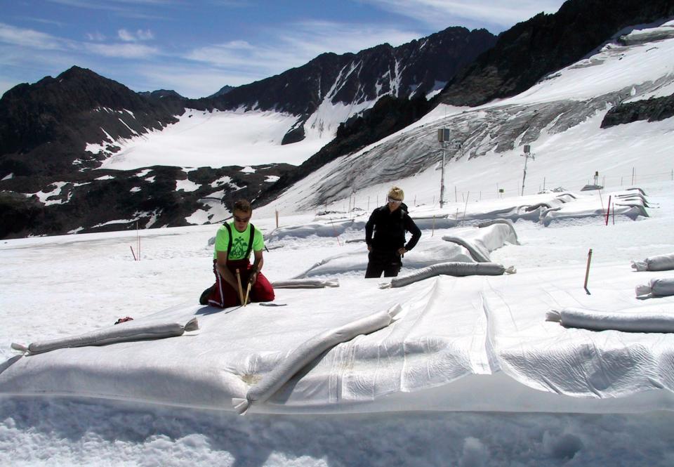 FILE - In this July 4, 2005 file photo Marc Olefs, left, and Andrea Fischer, researchers from the Innsbruck University check a field covered with white polyethylene against the backdrop of majestic jagged peaks at Eisgrat (Ice Spine) skiing station on Stubai glacier near the village of Neustift im Stubaital in the alpine Austrian province of Tyrol. It's Plan B in the fight against climate change: cooling the planet by sucking heat-trapping CO2 from the air or reflecting sunlight back into space. The U.N.’s expert panel on climate change is under pressure from both sides this week in Berlin, Germany, as it considers whether geoengineering should be part of the toolkit that governments use to keep global warming in check. (AP Photo/George Jahn, File)