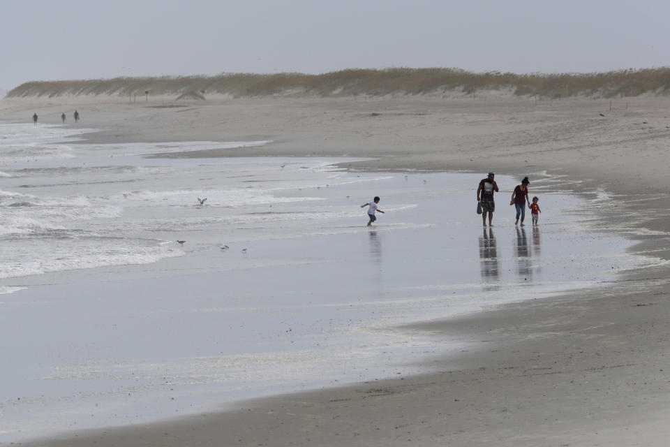 Personas juegan en la playa al acercarse la tormenta tropical Isaías en Kure Beach, Carolina del Norte, el lunes 3 de agosto de 2020. (AP Foto/Gerry Broome)