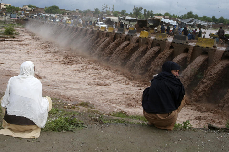 People looks a stream, which is overflowing following heavy rains, on the outskirts of Peshawar, Pakistan, Monday, April 15, 2024. Lightnings and heavy rains killed dozens of people, mostly farmers, across Pakistan in the past three days, officials said Monday, as authorities declared a state of emergency in the country's southwest following an overnight rainfall to avoid any further casualties and damages. (AP Photo/Muhammad Sajjad)