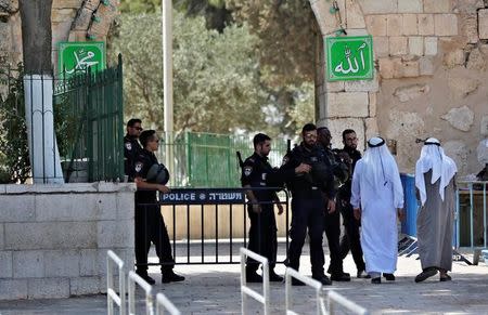 Palestinians walk next to Israeli security forces at the entrance of the compound known to Muslims as Noble Sanctuary and to Jews as Temple Mount at morning after Israel removed the new security measures there, in Jerusalem's Old City July 25, 2017. REUTERS/Ronen Zvulun