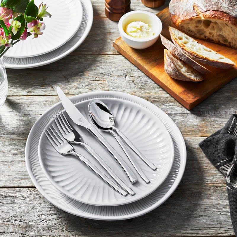 Table setting with plate, cutlery, and bread on a wooden board