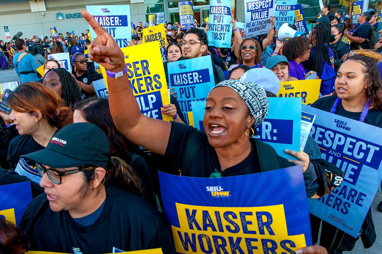 Workers carrying picket signs, chanting, and marching